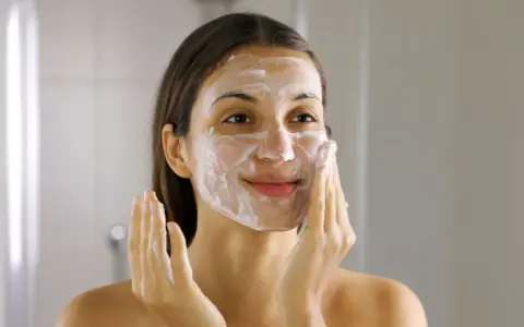Frau mit Schaum im Gesicht, die ihre Haut reinigt. Ein Schritt im Double Cleansing für reine Haut.