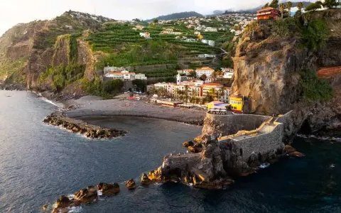 Ponta do Sol, Madeira: malerische Küstenstadt mit terrassierten Bananenplantagen, einem Kiesstrand und einer beeindruckenden Felsformation mit einem steinernen Aussichtsweg.
