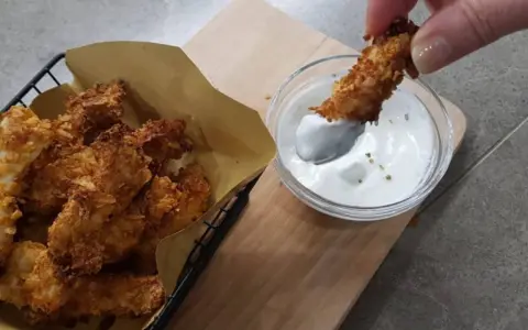 Bocconcini di pollo in friggitrice ad aria, croccanti e dorati, pronti per essere intinti in una salsa cremosa.