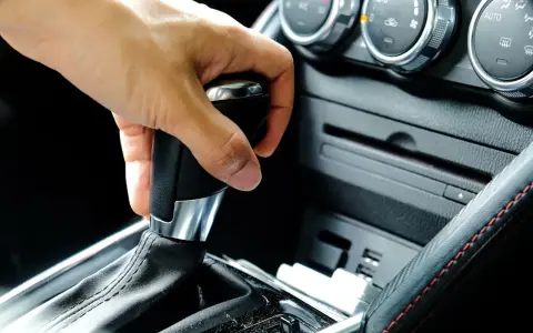 Mano operando la palanca de **cambio automático como funciona** en un coche moderno.