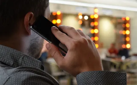Mężczyzna rozmawia przez telefon, zastanawiając się, co to jest catfishing i czy sam nie jest jego ofiarą.