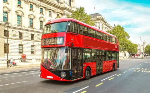 Ikoniczny czerwony autobus piętrowy na ulicy w Londynie, symbol komunikacji miejskiej.