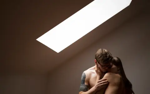Para objęta jest namiętnymi pieszczotami w świetle padającym z okna dachowego.