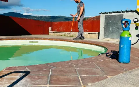 Técnico trabajando en el borde de una piscina, con equipo para impermeabilizar piscina.