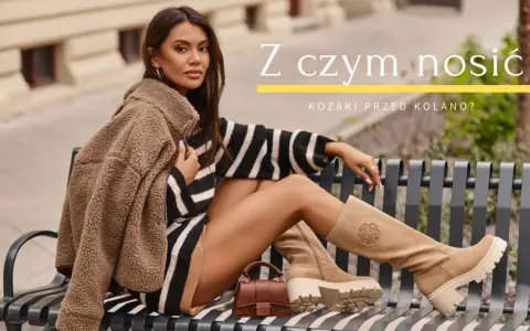 Kobieta w beżowych kozakach przed kolano, w stylizacji z kamizelką i sukienką w paski, pokazuje, z czym nosić kozaki przed kolano.