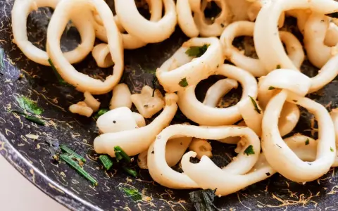 Anelli di totano in padella, dorati e profumati con erbe aromatiche, pronti per essere gustati.