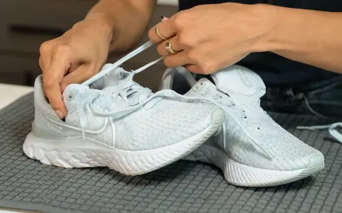 Hände ziehen Schnürsenkel durch hellblaue Mesh Schuhe. So einfach lassen sich die Lieblingssneaker reinigen.
