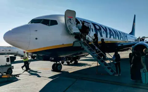 Ryanair samolot, pasażerowie wsiadają. Pamiętaj o zasadach, jak przewozić leki w samolocie Ryanair, by podróż przebiegła sprawnie.