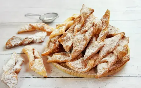 Faworki croccanti e dorati, spolverati di zucchero a velo. Un delizioso dolce da preparare seguendo un semplice faworki przepis.