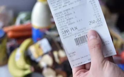 Ręka trzyma paragon z zakupów spożywczych, na którym widnieje suma 250,02 zł. Zastanawiasz się, gdzie wyrzucać paragony? Ten jest z papieru termicznego.