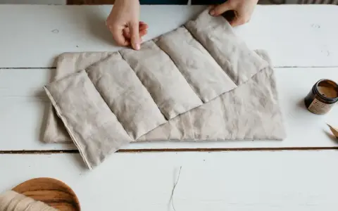 Mains tenant une bouillotte graines de lin, prête à soulager les tensions. Un objet doux et naturel pour le bien-être.