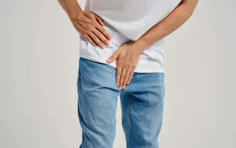 Mężczyzna trzyma się za podbrzusze, co może sugerować zapalenie prostaty objawy.