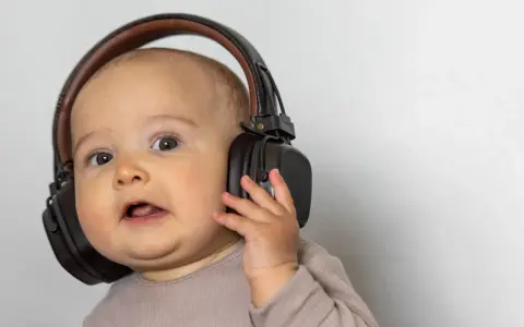 Un bébé curieux avec un casque anti-bruit. Quand utiliser un casque anti-bruit bébé à partir de quel âge ?