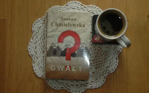 Kawa i książka Joanny Chmielewskiej "Gwałt" na koronkowym obrusie. Idealny zestaw do czytania jej kryminałów chronologicznie.