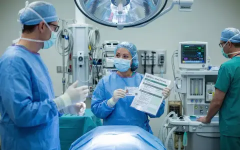 Zespół medyczny na bloku operacyjnym omawia checklistę bezpieczeństwa. Dodatek za pracę na bloku operacyjnym jest kluczowy dla bezpieczeństwa pacjenta.