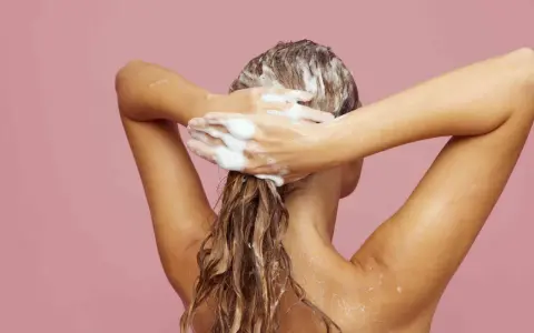 Frau wäscht sich die Haare mit Schaum. Ein Hauch von Friseur Puder für Volumen.