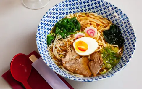 Miseczka zupy ramen z makaronem, jajkiem, mięsem, warzywami i nori.