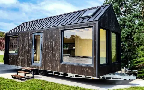 Nowoczesny tiny house w Polsce, z ciemną drewnianą elewacją i dużymi oknami, gotowy na przygodę.