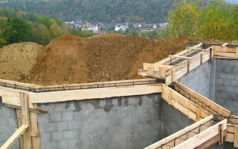 Fundamenty domu w budowie, zbrojenie i szalunki czekają na beton. Widać, ile jest ważne pozwolenie na budowę, by móc rozpocząć taką inwestycję.