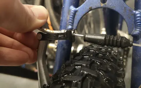 Dłoń reguluje linkę hamulca v-brake, by wyeliminować piszczące hamulce w rowerze.
