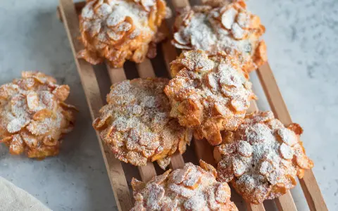 Dolci croccanti, simili a rose del deserto, ricoperti di fiocchi di mais e spolverati di zucchero a velo.