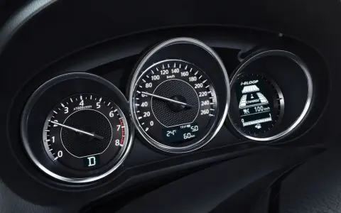 Zbliżenie na deskę rozdzielczą samochodu: obrotomierz pokazuje ok. 1500 obr./min, prędkościomierz ok. 60 km/h, a wyświetlacz i-ELOOP informuje o ładowaniu.
