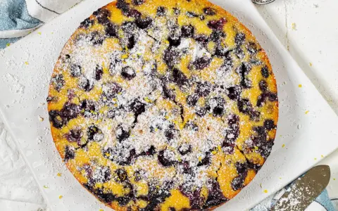 Ein köstlicher glutenfreier Kuchen mit Blaubeeren und Puderzucker bestreut, bereit zum Genießen.