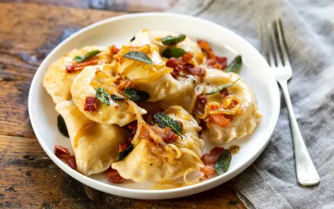 Pyszne pierogi z boczkiem i cebulką, idealne na obiad. Dowiedz się, ile gotować pierogi, by były idealne.