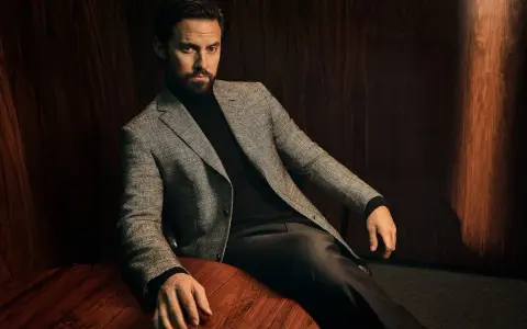 A man in a tweed blazer and dark trousers, showcasing sophisticated trouser styles.