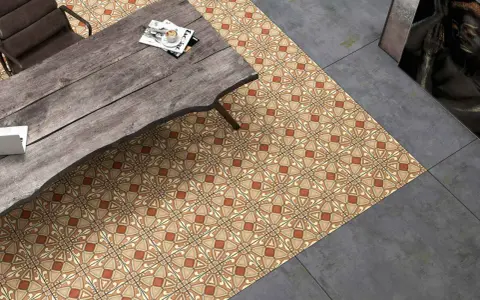 Un suelo hidráulico con diseño geométrico en tonos tierra y ocre, junto a un suelo de cemento pulido. Una mesa de madera rústica y una silla completan la escena.