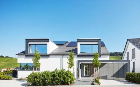 Moderner Hausbau mit Solaranlagen auf dem Dach. Ein Architekt hat hier ein stilvolles Einfamilienhaus mit Garage und gepflegtem Garten entworfen.