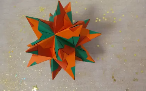 Ein sternförmiges Origami-Objekt in Orange und Grün, das an einen funkelnden Winterhimmel erinnert.