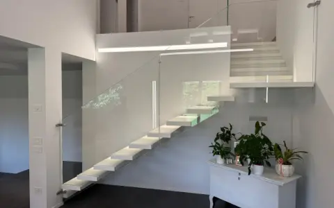 Moderna scala interna con gradini sospesi e parapetto in vetro, un esempio di come la normativa scale interne uso privato possa ispirare design eleganti e sicuri.