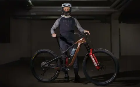 Kolarz w kasku i odzieży rowerowej prezentuje nowoczesny rower MTB. To sprzęt do ekstremalnej jazdy, a rowery mtb co to znaczy? To rowery górskie do trudnych tras.