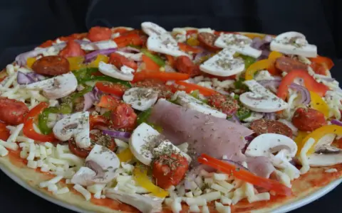Pizza maison aux épeautre, garnie de champignons, poivrons, oignons, jambon et chorizo.