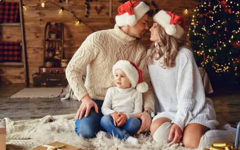Una familia con gorros navideños, junto a un árbol de Navidad, crea una foto navidad original llena de amor y calidez.