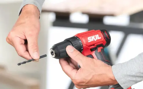 Man insertando una broca en un taladro inalámbrico rojo de la marca SKIL.