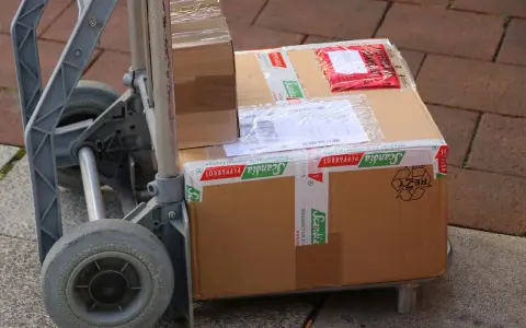 Paczki na wózku, gotowe do wysyłki. Ubezpieczenie paczki DHL to pewność, że dotrze bezpiecznie.