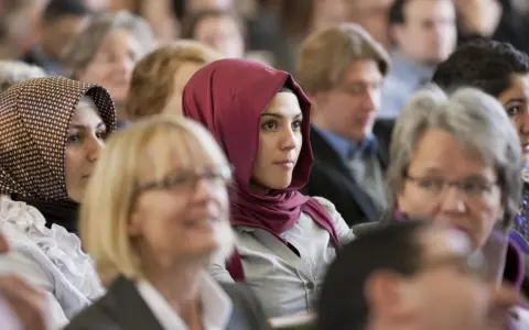 Junge Frau mit einem roten islamischen Kopftuch im Publikum.