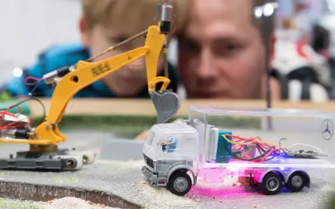 Faszination auf der **Hobby Messe Leipzig**: Ein Junge und ein Mann bestaunen eine ferngesteuerte Baustelle mit Bagger und LKW.