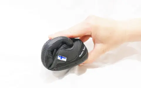 En hand håller en svart barfotasko med finska flaggan. Är barfotaskor bra eller dåligt?