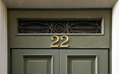Złote **anielskie liczby** 22 na zielonych drzwiach.