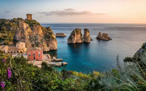 Scopri dove andare in vacanza in Italia: un borgo con torri antiche e faraglioni su un mare cristallino.
