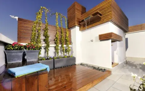 Jardineras de exterior con flores rojas y enredaderas. Un espacio moderno con ducha y terraza de madera.