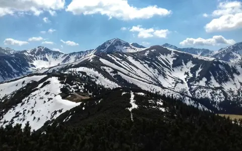 Majestatyczne Tatry w kwietniu, pokryte śniegiem szczyty i zielone lasy.
