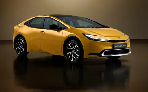 Złoty Toyota Prius Plug-in Hybrid z czarnym dachem, nowoczesnymi światłami i stylowymi felgami.