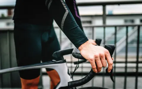 Rowerzysta z silnym bólem ud po jeździe na rowerze, trzymający kierownicę.