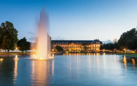Ein beleuchteter Brunnen spiegelt sich im Wasser vor dem Neuen Schloss in der Stuttgarter Innenstadt.