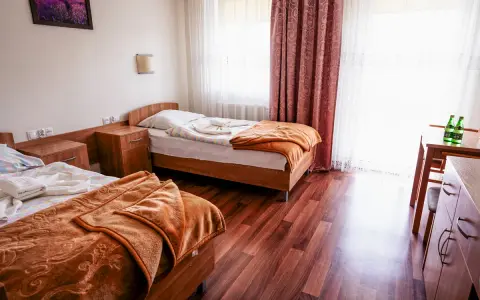 Pokój w sanatorium Busko-Zdrój, prywatnie Krystyna. Dwa łóżka, szafki nocne, stół z krzesłem i butelkami wody.