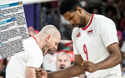 Daniel Stępień, siatkarz w białej koszulce z numerem 9 i godłem Polski, świętuje z kolegą z drużyny.